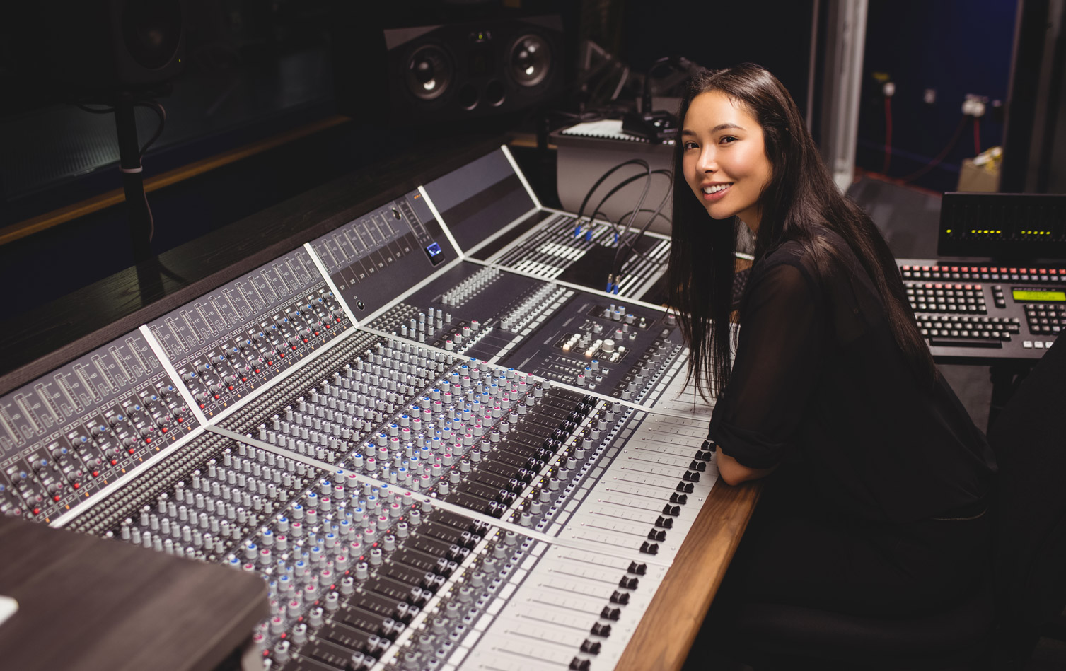 A student sits at the controls of a professional audio mixing console.